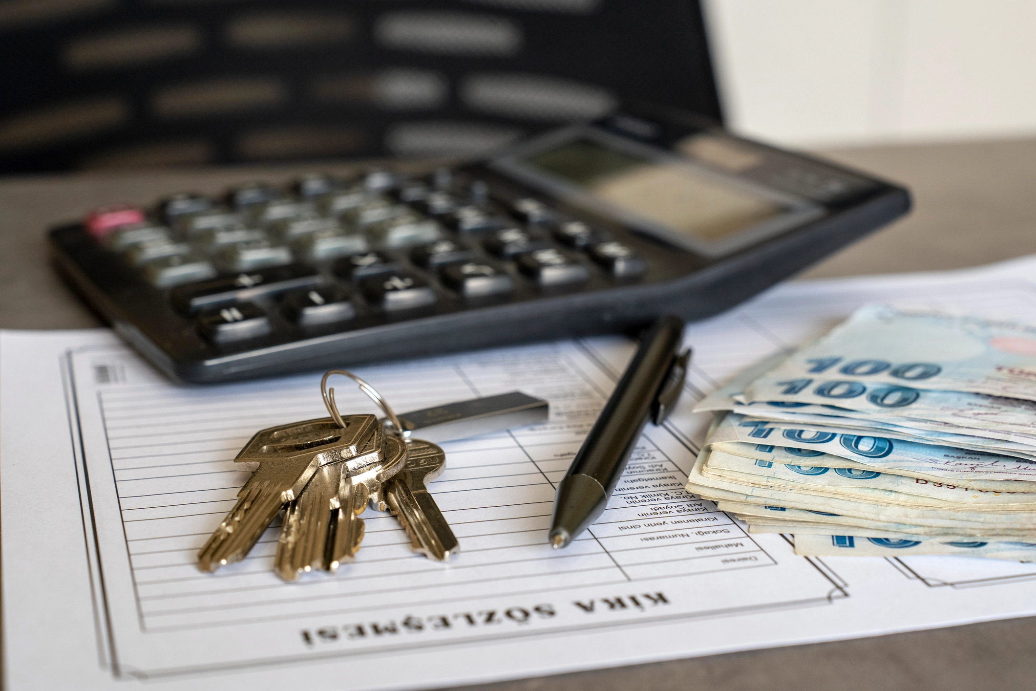 Calculator, keys, and cash on mortgage refinance paperwork