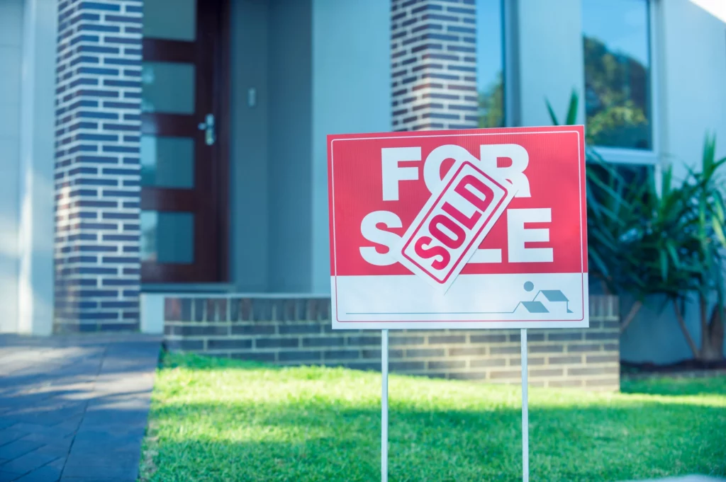 For sale sign with sold sticker in front of modern house, representing fast refinance success