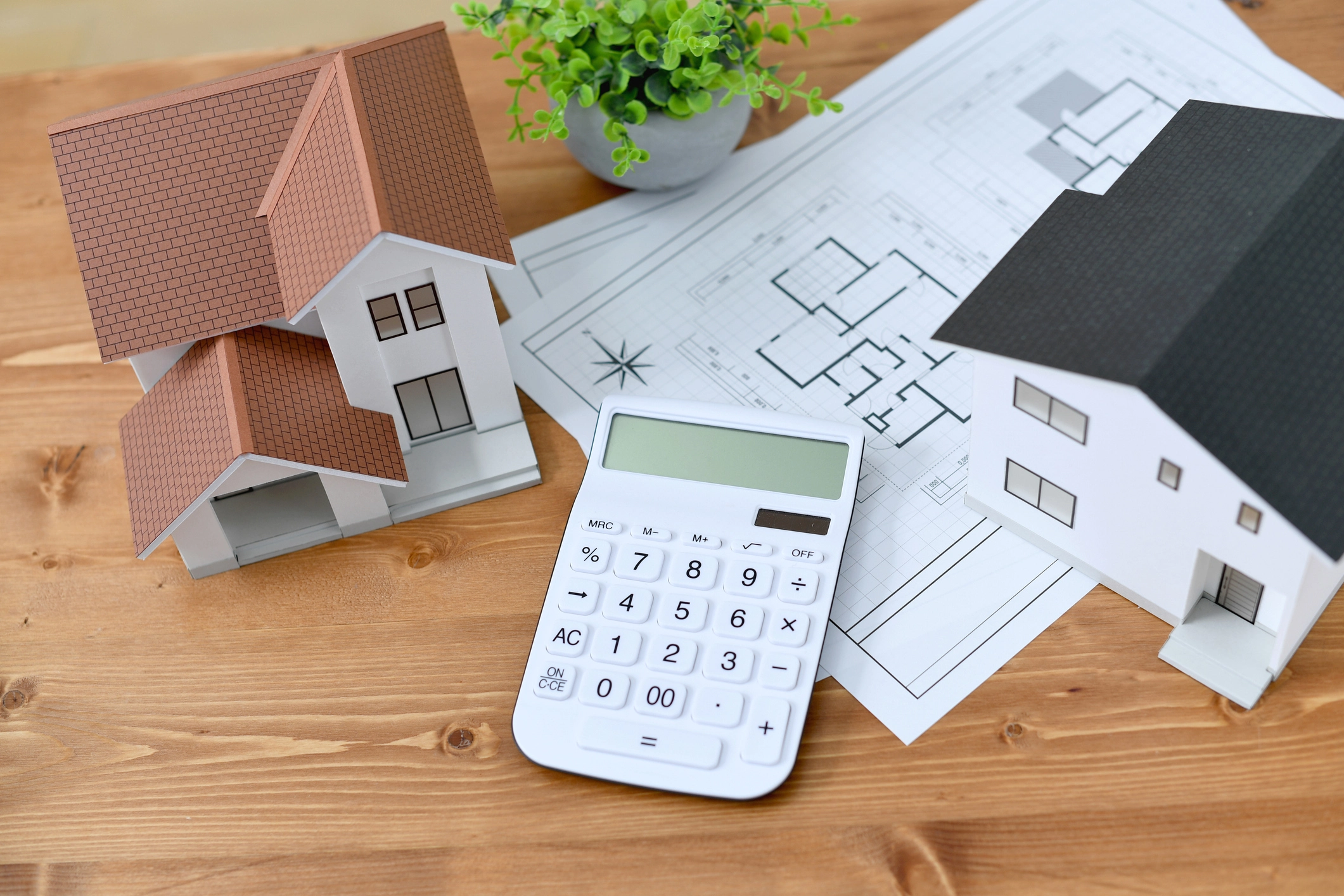 Model houses and calculator on architectural plans, symbolizing home equity loan calculations and financial planning