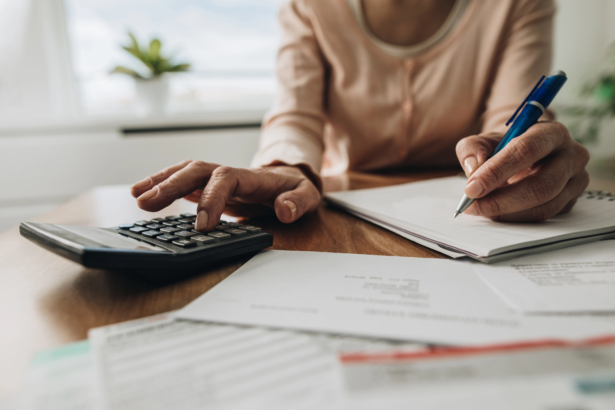 Person calculating finances with a calculator and notepad, representing financial planning for Low Doc Home Loans